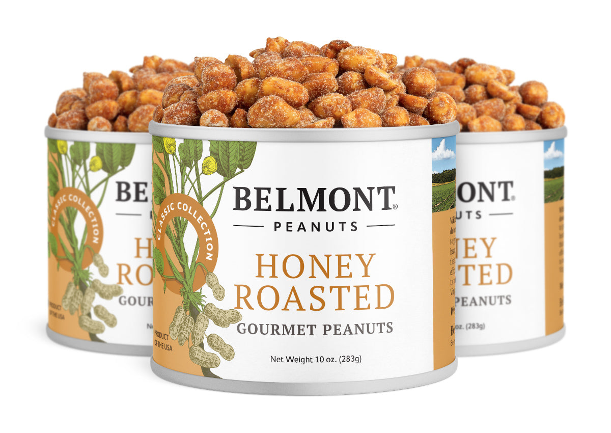 Three cans of Honey Roasted peanuts are displayed, with the front can in focus. The white and gold label showcases jumbo peanuts inside, each filled with delicious honey roasted flavor.