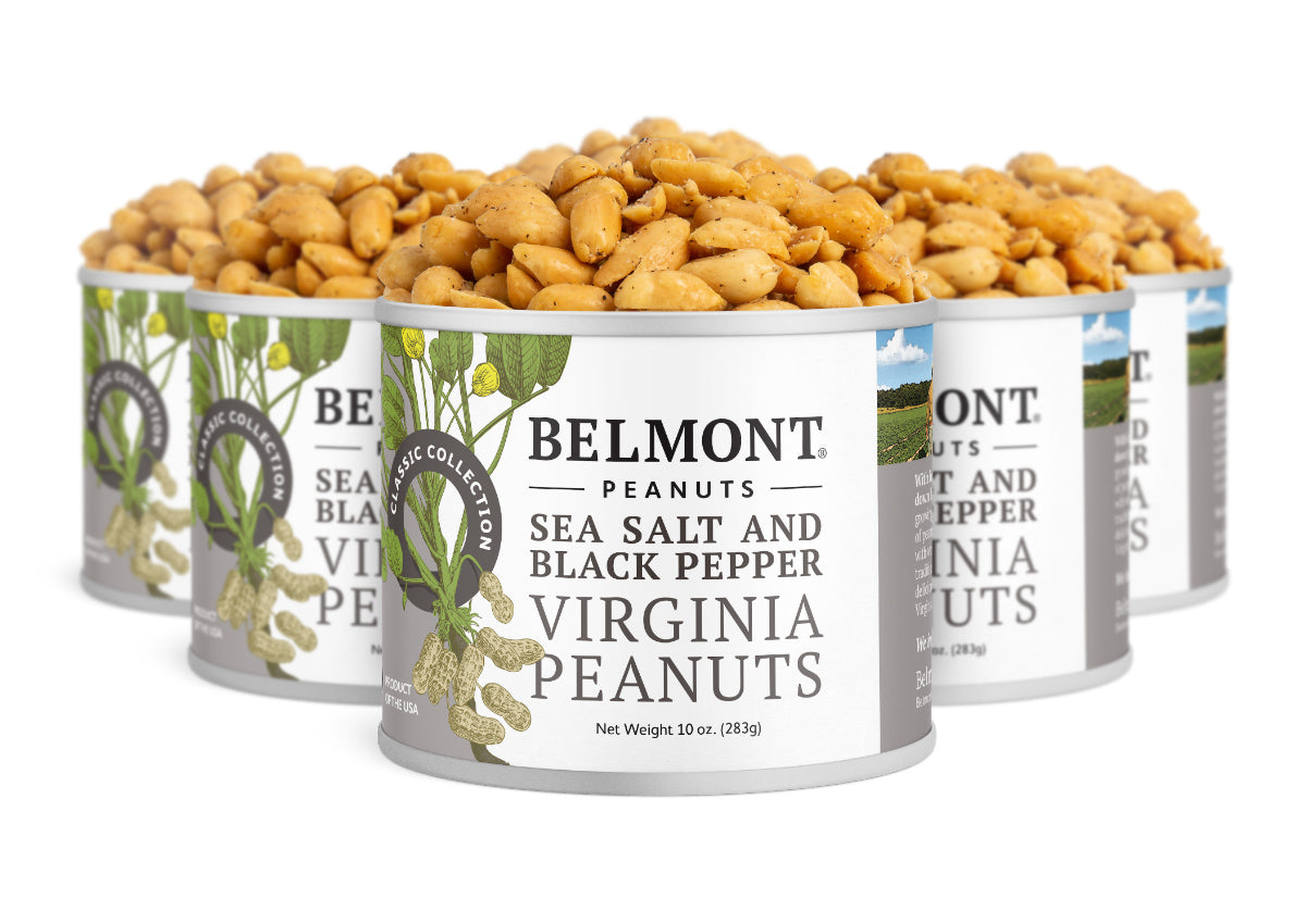 Five open cans of Sea Salt & Black Pepper peanuts are stacked, overflowing with peanuts. The cans’ labels feature charming peanut plant illustrations.