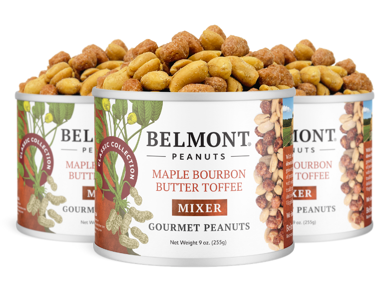 Three cans of Maple Bourbon Butter Toffee Mixer are displayed in a staggered row, with the front label highlighting the butter toffee peanuts and maple bourbon spice.
