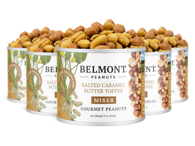 Four cans of Salted Caramel Butter Toffee Mixer, with peanuts piled above the open cans. Each can displays a decorative label with charming peanut and caramel illustrations.