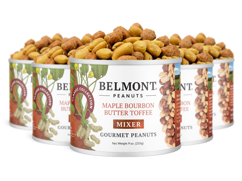 Four cans of Maple Bourbon Butter Toffee Mixer are arranged in a staggered row, their labels with illustrated peanuts and maple leaves evoking the sweet, spiced flavor of these gourmet candied peanut treats.