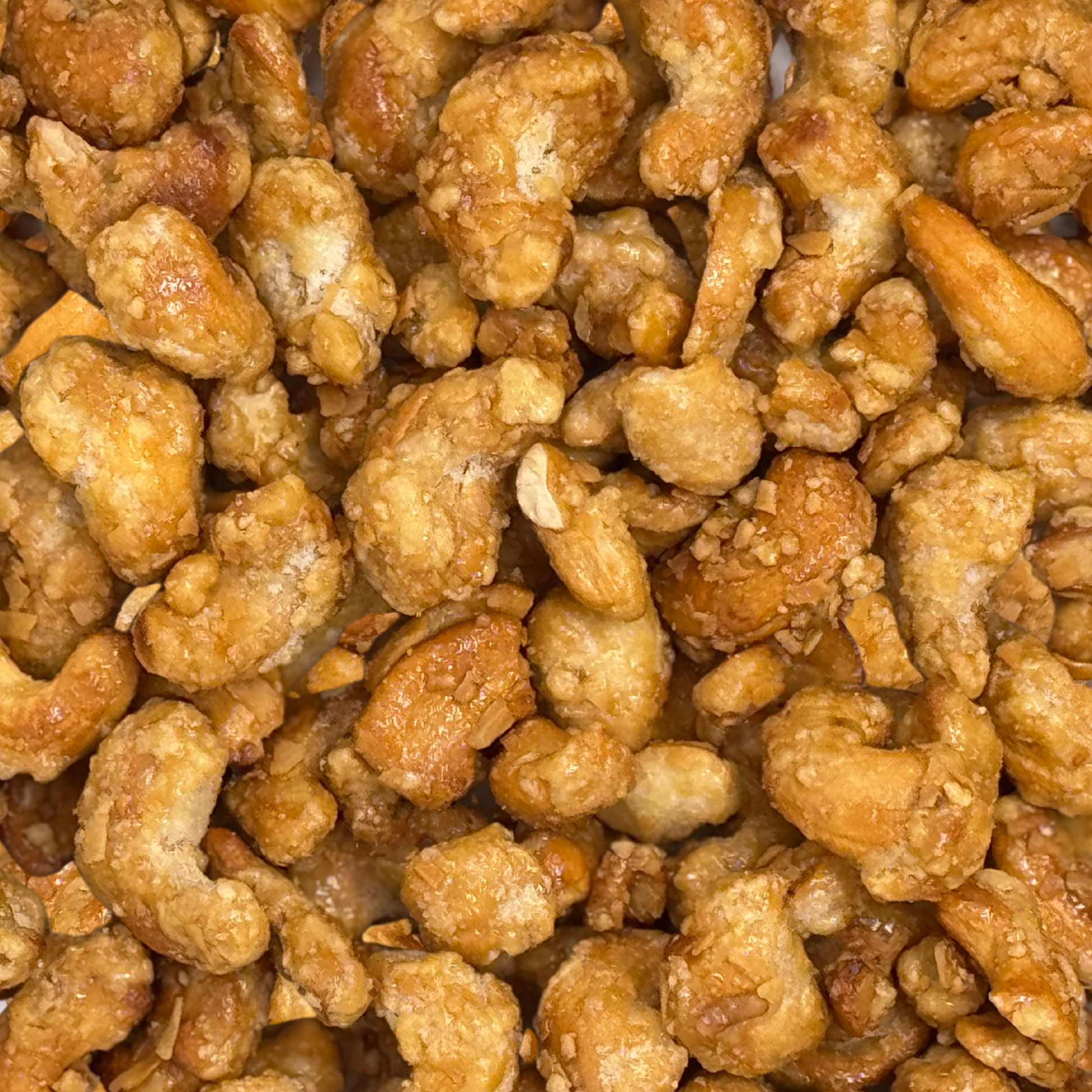 Close-up of Coconut Glazed Candied Cashews, coated in a glossy, coconut-infused caramelized sugar. The golden brown nuts cluster together, showing off their crunchy texture and irresistibly sweet, tropical coating.