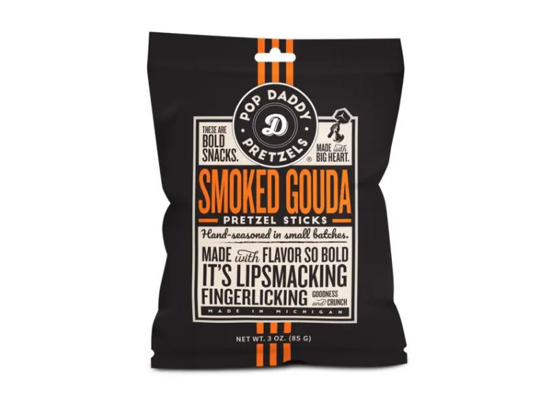 A black 3 oz bag of Smoked Gouda Pretzel Sticks features bold orange and white text, highlighting creamy-smooth flavor and small-batch seasoning for lip-smacking pretzels in every bite.