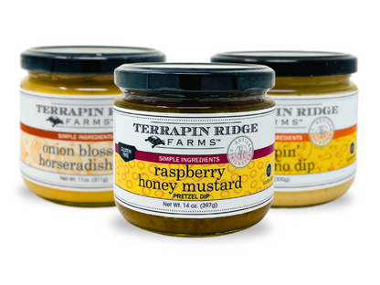 A jar of Raspberry Honey Mustard by Terrapin Ridge Farms is featured in front, with two other Terrapin Ridge Farms gourmet condiment jars—Onion Blossom Horseradish Dip and Sriracha Horseradish Dip—blurred in the background.