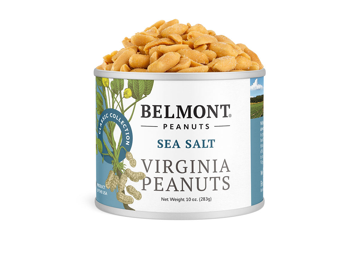 A can of Sea Salt gourmet peanuts sits open with peanuts spilling out. The label shows Virginia peanuts and green leaves, and lists the net weight as 10 oz (283g).