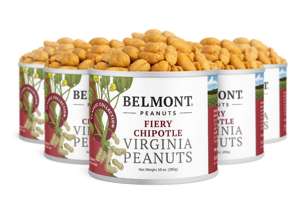 Five cans of Fiery Chipotle peanuts are grouped together, featuring red accents and a peanut plant illustration, with protein-packed, roasted snacks spilling from the tops.