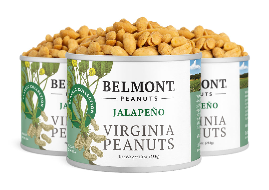 Three cans of Jalapeno peanuts are displayed, with the front can in focus. The cans are white with green text and feature images of peanuts on the vine, containing peppery jalapeno peanuts roasted to perfection.