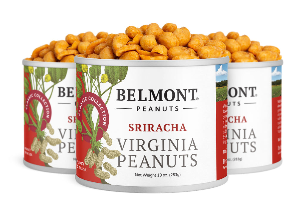 Three cans of Belmont Peanuts Sriracha are shown, filled to the top with seasoned peanuts. Each can features a botanical peanut illustration on a white label accented with red chili peppers.