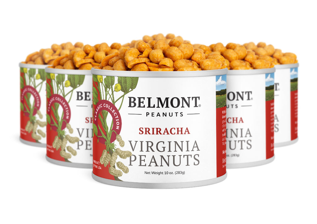Several cans labeled "Sriracha" are arranged closely together, lids open to reveal seasoned peanuts inside. The red and white labels display images of peanuts, leaves, and a hint of red chili pepper.