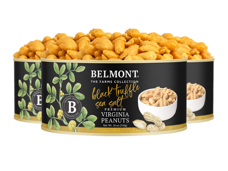 Three cans of Black Truffle Sea Salt peanuts are displayed, with the front can featuring a label of sea salt peanuts, green leaves, and gold and white text on a sleek black background.