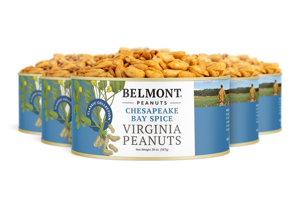 Four cans of Chesapeake Bay Spice are arranged in a staggered row, with the front can in focus displaying the label and seasoned peanuts topped with zesty crab spice seasoning.