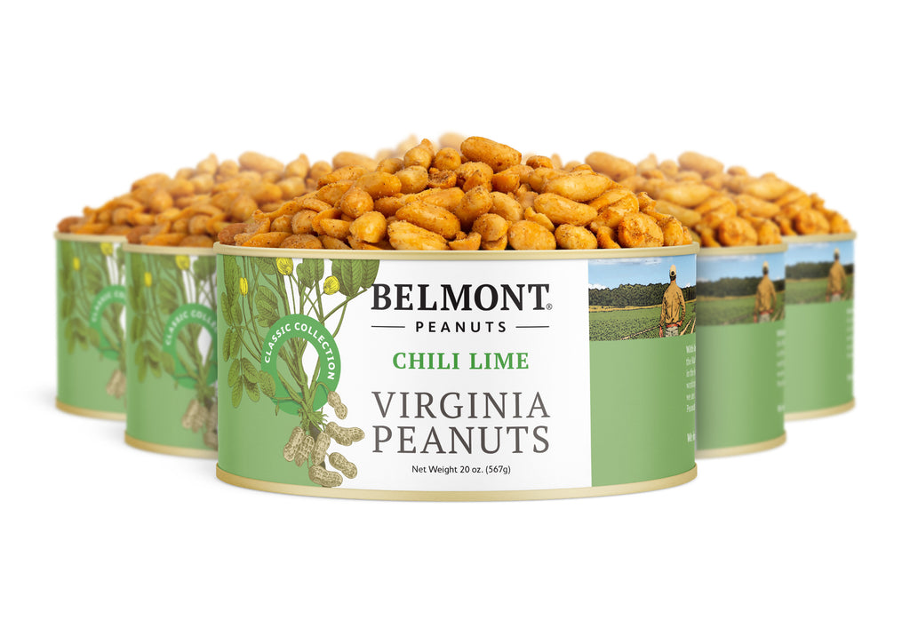 Four cans of Chili Lime peanuts are arranged in a semi-circle, with the front can open and spilling out seasoned snacks. The green-accented label highlights peanut plants and the product name, Chili Lime.