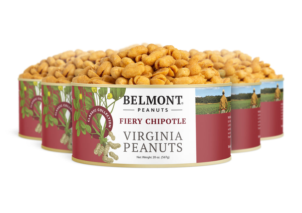Four cans of Fiery Chipotle are arranged in a row. The red and white labels display images of peanuts and a farmer, emphasizing these protein-packed snacks.