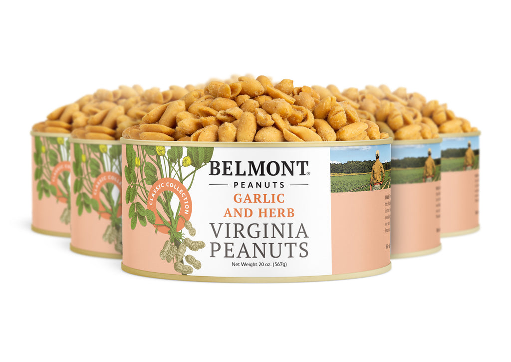 Four cans of Garlic & Herb gourmet Virginia peanuts are grouped together. Each can features a peanut plant and farmer illustration and is filled with protein-rich roasted peanuts visible at the top.