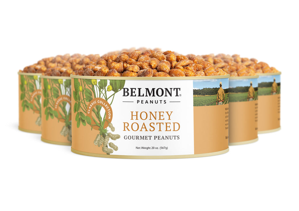 Four cans of Honey Roasted peanuts are displayed, each filled with jumbo peanuts. The labels show green peanut plants and a farmer standing in a field.