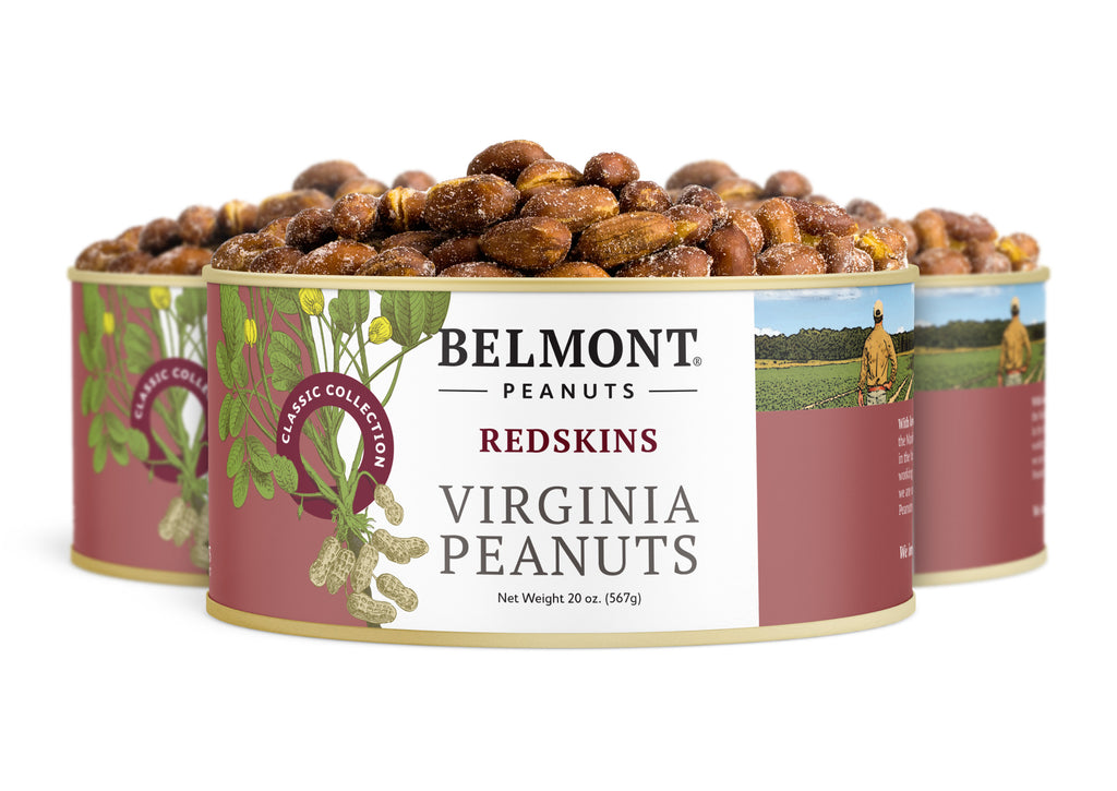 Three cans of Redskins are shown, each filled with roasted All-Natural Redskin peanuts. The label displays peanut illustrations and a farmer in a field, emphasizing their rich nutrients and essential vitamins.