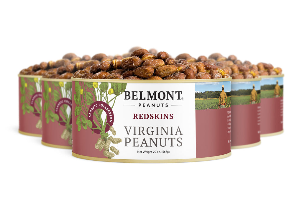 Three tins of Redskins roasted peanuts are shown, with packaging featuring peanut illustrations and a farmer's photo in a field, highlighting essential vitamins and nutrients.