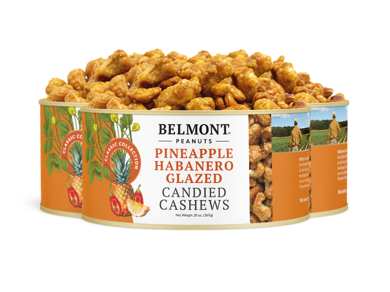 Three tins of Pineapple Habanero Glazed Candied Cashews, featuring a vibrant orange label with pineapples, habanero peppers, and cashews, with these spicy candied cashews spilling temptingly from the open tin.