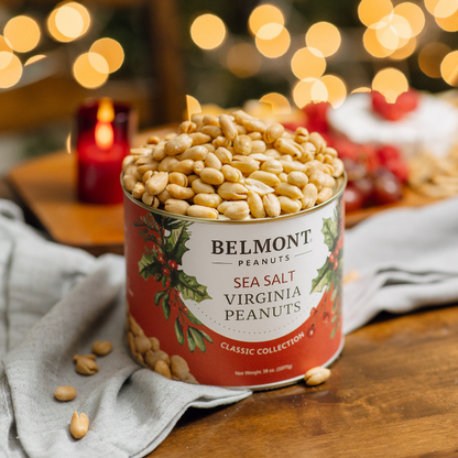 Can of Belmont Peanuts with festive design on a wooden table with blurred lights in the background