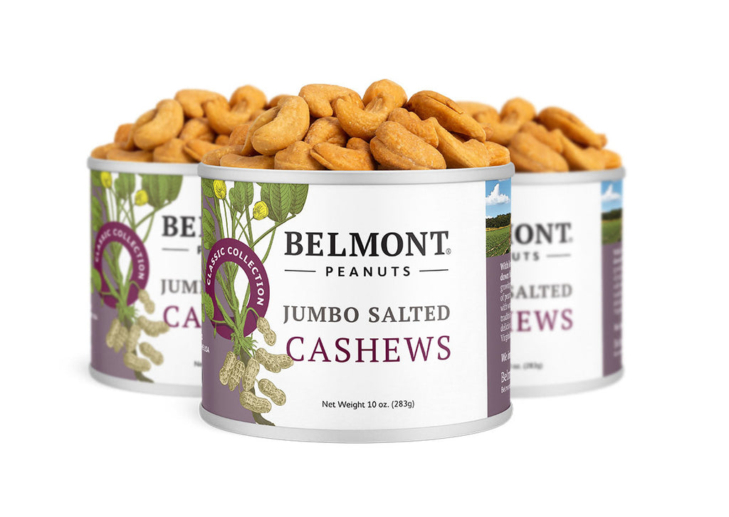 Three cans of Jumbo Salted Cashews are displayed, each with a white label featuring cashew and green leaf illustrations. The staggered arrangement makes them an ideal choice for a healthy snack.