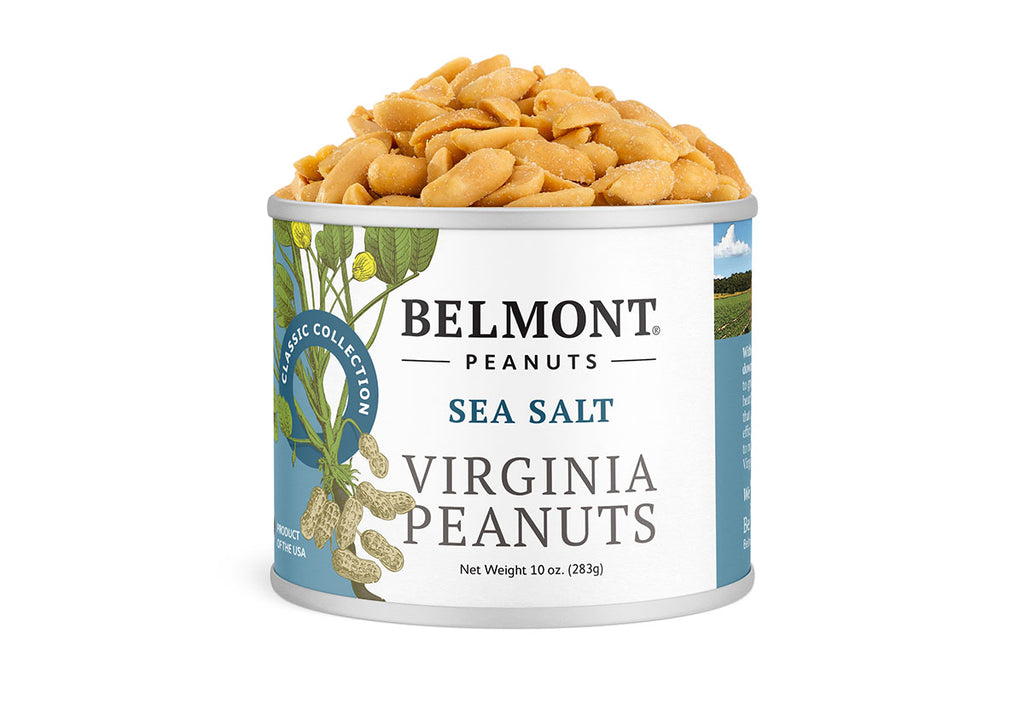 A can of Sea Salt gourmet peanuts sits open with peanuts spilling out. The label shows Virginia peanuts and green leaves, and lists the net weight as 10 oz (283g).